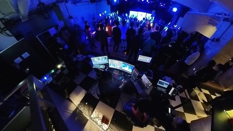 Live event control position overlooking a blue-lit audience and stage