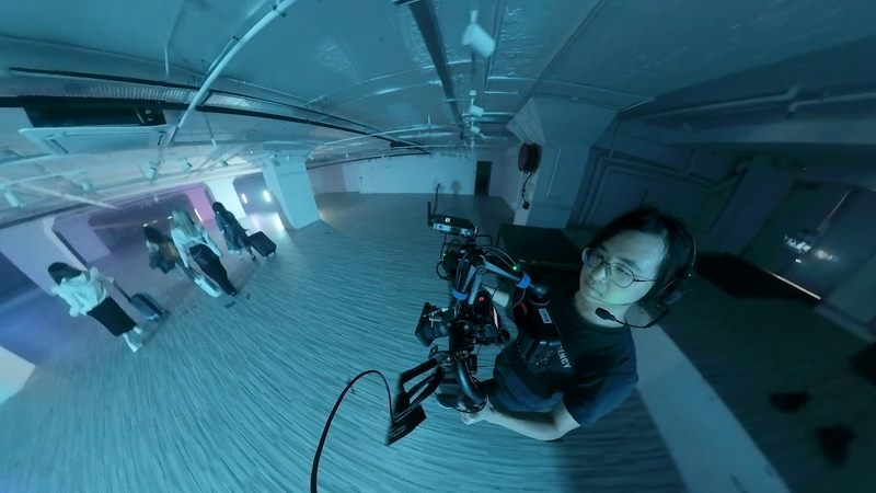 Camera operator filming performers in a blue-lit music video set
