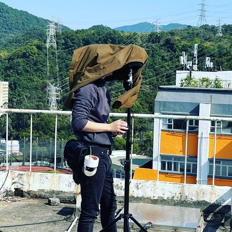 Crew member adjusting a rooftop light stand under daylight