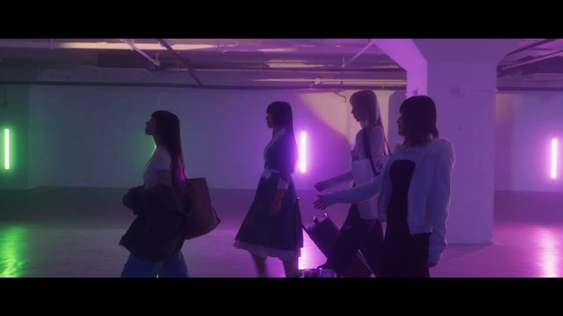 Still from Dopamine official music video with performers walking through purple and green light